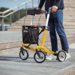 Gelber Carbon-Rollator Gepard im Einsatz auf einem Holzsteg mit Stufen